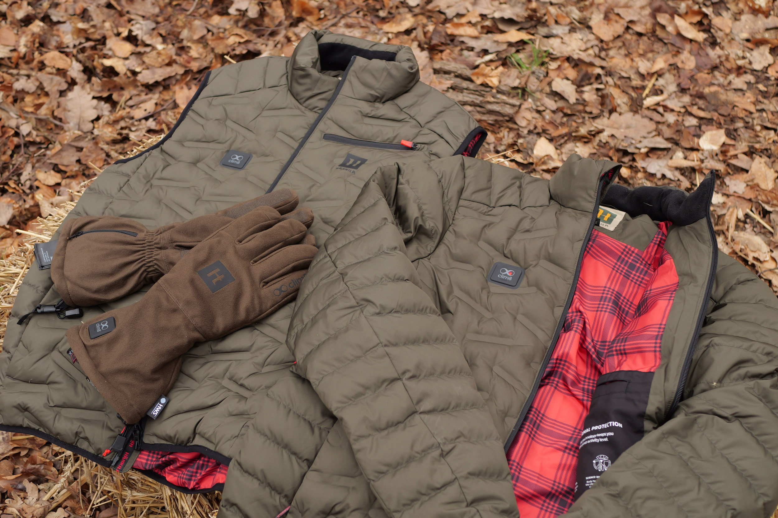 Die Heizhandschuhe, Heizjacke und Heizweste der clim8-Serie von Härkila neben-/aufeinander drappiert