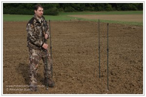 Jäger beim Aufstellen der Teleskopstangen eines Tarnschirms für die Flugwildjagd am freundlichen Lockbild
