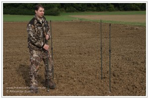 Jäger beim Aufstellen der Teleskopstangen eines Tarnschirms für die Flugwildjagd am freundlichen Lockbild