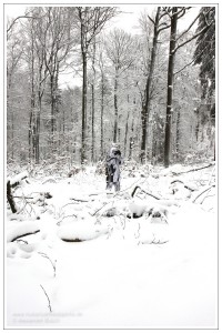Gut getarnter Jäger im Schneetarnanzug pirscht im verschneiten Wald