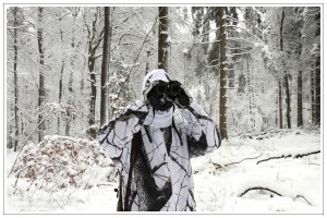 Jäger in Schnee glast den verschneiten Wald ab