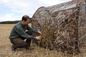 Jäger beim Verblenden des Ameristep Hayhouse Blinds in Max-4 ® auf einem Stoppelacker