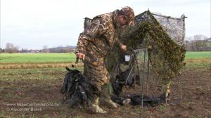 Jäger mit erlegten Krähen am Tarnstand