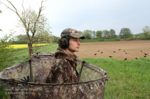 Jäger schaut über den Rand eines Tarnstandes bei der Krähenjagd