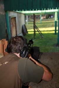 Ein Schütze zielt im Schießstand mit angeschlagenem und abgestütztem Gewehr auf eine Anschussscheibe