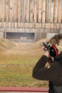 Eine Schützin auf dem Schießstand, stehend, bei Schussabgabe mit dem Gewehr