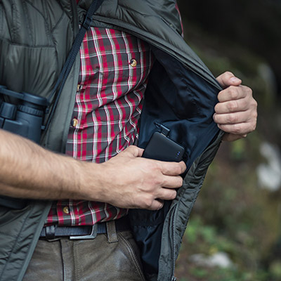 Eine Powerbank wird in die Innentasche einer Deerhunter-Heizjacke mit HEAT-Funktion gesteckt.