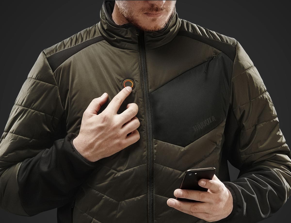 Detailansicht einer Härkila-HEAT-Control-Heizjacke mit Einstelltaste und Smartphone.